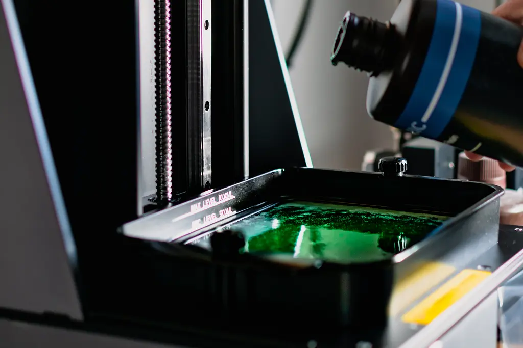 Impression 3D SLA 12K – impression précise d'un vase orange en résine, tête d'imprimante 3D visible.